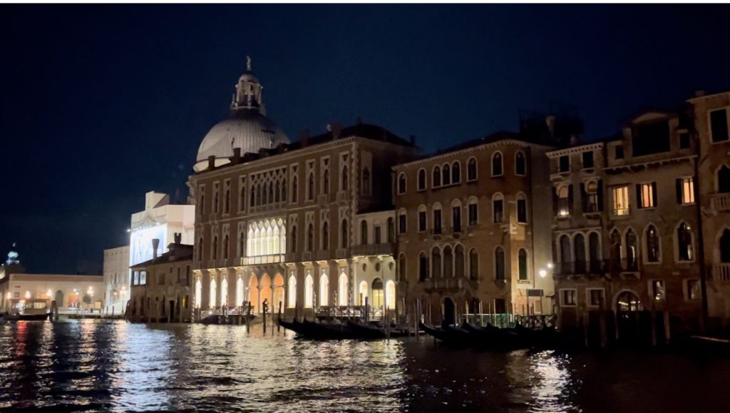 A night view of Venice with buildings lit up and reflecting in the water